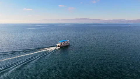 Aerial drone view of a small passenger boat with a blue canopy glides across the Stock Footage 324582541