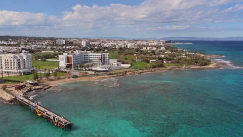 Aerial drone view of a small pier extending into clear turquoise waters along Видео 331797363