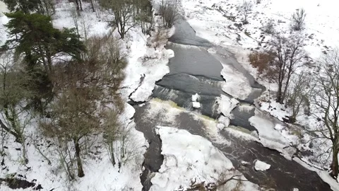 Aerial drone view of a small stream in the winter with snow all around. Stock Footage 172204617