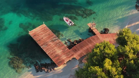Aerial drone view of a small white boat moored to a wooden pier above the Stock Footage 324571550