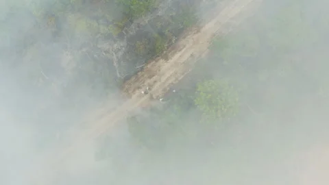 Aerial drone view of a smoke-covered dirt road in the southern Amazon Stock Footage 340276517