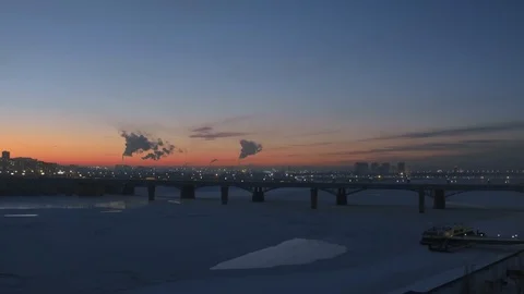 Aerial drone view of snow covered night city. Winter frozen river, red sunset Stock Footage 102327351