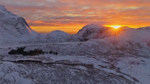 Aerial drone view of snow-covered mountains and golden sunrise sky 動画素材 345721781