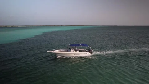Aerial drone view of a speedboat navigating through turquoise waters toward a Stock Footage 346334110
