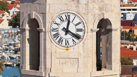 Aerial drone view of a stone clock tower featuring a large white clock face with Stock Footage 324609505