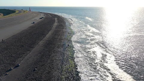 Aerial drone view of sun glinting on ocean waves rolling against a wide stone Video stock 336214707