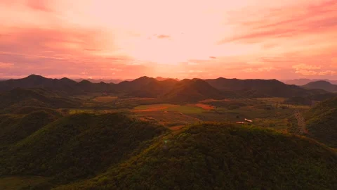 Aerial drone view of sun setting over lush mountain valley with vivid pink sky Stock Footage 314973858