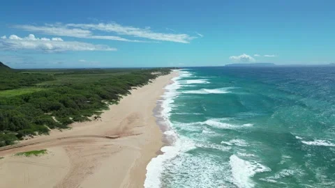 Aerial drone view of surf rolling toward a long empty beach in Hawaii Stockbeeldmateriaal 347825962