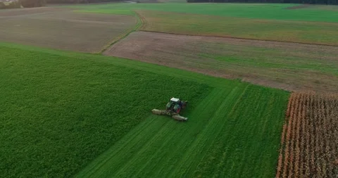 Aerial drone view of tractor cutting green grass on farming field Stock Footage 144985876