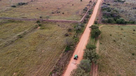 Aerial drone view of tractor dragging old tyres to repair dirt road Stock Footage 337143440