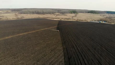 Aerial drone view of a tractor harrowing a chernozem field. Taken in the spring Stock Footage 130250092