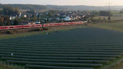 Aerial Drone View of a Train besides A Big Solar Park For Renewable Energy 動画素材 118495818