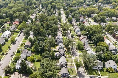 Aerial drone view of tree-lined residential neighborhood with detached homes and Photos