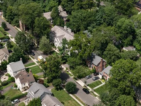 Aerial drone view of tree-lined residential neighborhood with detached homes Stock-Fotos