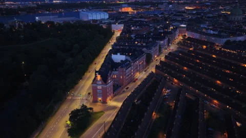 Aerial drone view of the triangular building lit up at night along Oster Stock Footage 316349614