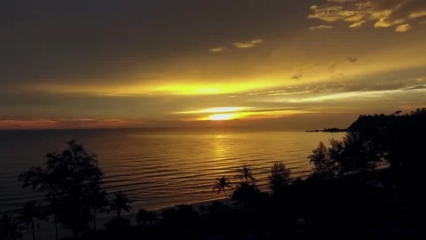Aerial drone view of tropical sunset over calm ocean waves and silhouette palms Stock Footage 345552803