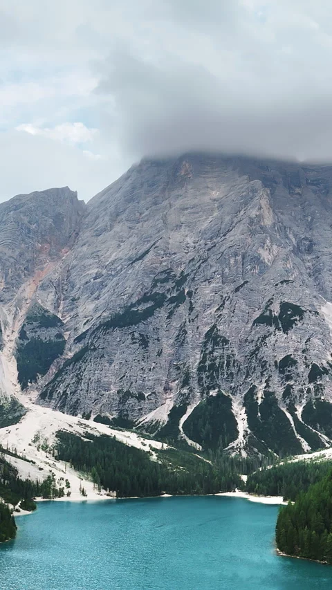 Aerial drone view of a turquoise alpine lake surrounded by steep rocky mountains Stock Footage 332313732