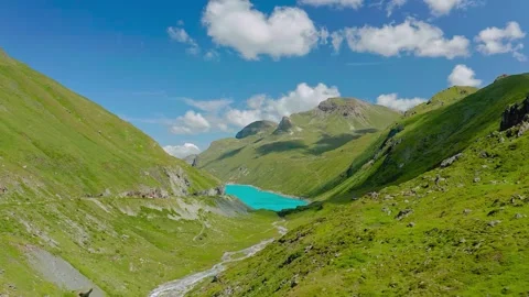 Aerial drone view of turquoise alpine lake in lush green mountain valley 库存影片 345100888