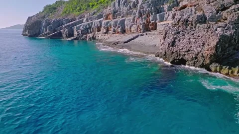 Aerial drone view of turquoise ocean waves washing rocky coastal cliffs Stock Footage 345292870