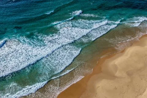 Aerial drone view of waves rolling onto the sandy shoreline at Nobbys Beach.. Stockfoto's