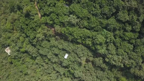 Aerial drone view of a white cable car ride over a lot of vegetation between mou Stock Footage 198778645