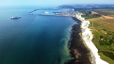 Aerial drone view of the white chalk cliffs above a dark rocky shore and the Stock Footage 344954420