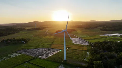 Aerial drone view of a white wind turbine silhouetted against a golden sunset Stock Footage 336665458