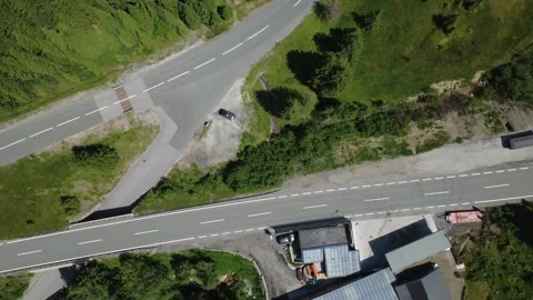 Aerial Drone View of a Winding Mountain Road Through Green Alpine Forests Stock Footage 338387892