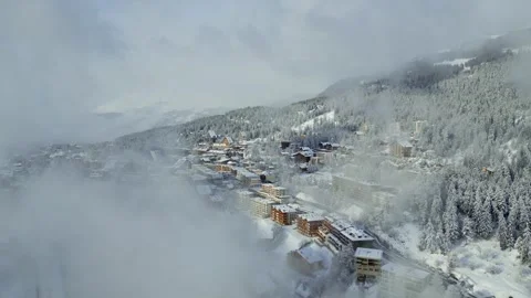 Aerial drone view of a winter alpine town emerging through misty clouds Stock Footage 301080494