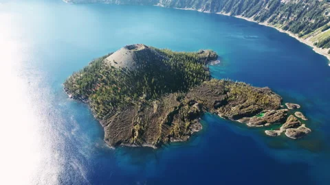 Aerial drone view of Wizard Island volcano cone rising from the deep blue waters Stock Footage 330802163