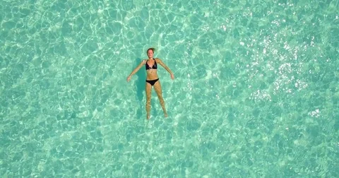 Aerial drone view of a woman floating and swimming on a tropical island. Stock Footage