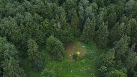 Aerial drone view of young man sitting near bonfire and tent Stock Footage 247136804