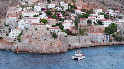 Aerial Drone Zoom View of Hydra Town Historic Walls and Catamaran Departing Stock Footage 344066956