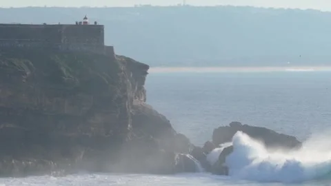 Aerial drone zoom view of waves crashing on rocks at North Beach in Nazare Stock Footage 295851652