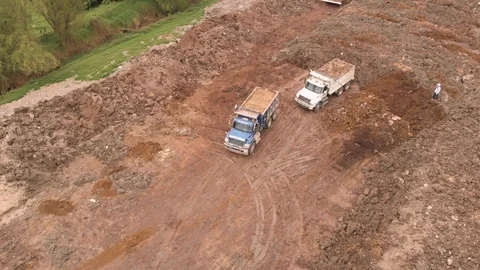 Aerial of dump trucks moving in reverse direction to unload the earth for Stock Footage 126491041