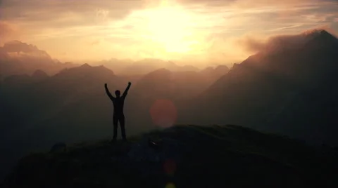 Aerial, edited - Triumphant hiker standing on top of the mountain raising arms Stock Footage