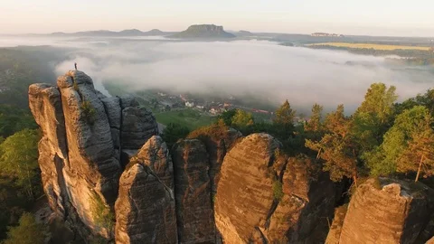 Aerial of Elbe Sandstone Mountain surrounded by green trees on a foggy day Stock Footage 116192588