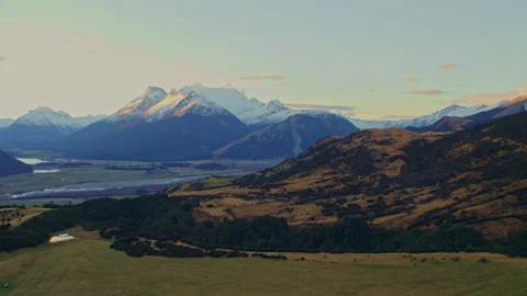 Aerial elevating up alpine slope at dusk revealing mountains in distance Stock Footage 155331224