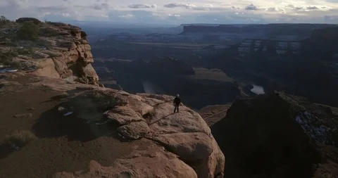 Aerial - epic flyover of a man standing alone on high cliffs at sunset Video stock 107112103