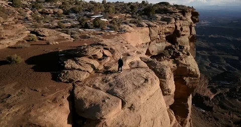 Aerial - epic orbit of a man standing on huge dramatic stone cliffs Stock Footage 107113105