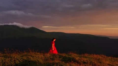 Aerial Epic shot. Camera moves around young woman standing victoriously on top Stock Footage 136777320