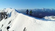 Aerial - Epic Shot Of Two Adult Male Mountaineers Hiking On Snowy Mountain Top Stock Footage
