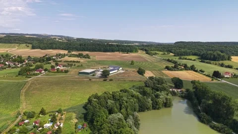 Aerial farmland panorama of patchwork fields, winding river, farm buildings, and Stock Footage 348504175