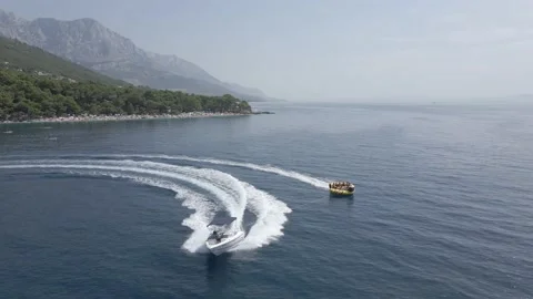 Aerial. Fast moving boat pulling tube on a sea. Tubes, towables Stock Footage 214324872