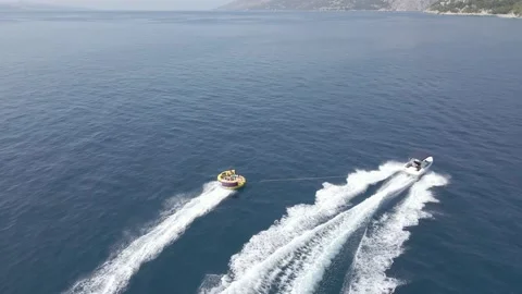 Aerial. Fast moving boat pulling tube on a sea. Tubes, towables Stock Footage 214675875