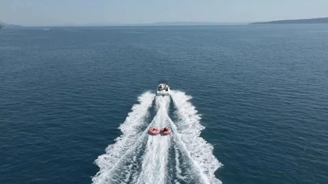 Aerial. Fast moving boat pulling tubes on a sea. Tubes, towables Stock Footage 250264495