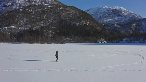 Aerial fast orbiting around man ice skating on idyllic scenery on Video stock 149052695