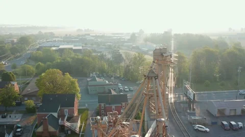 Aerial of feed mill, grain elevator by railroad tracks in small town in Stock Footage 155297663