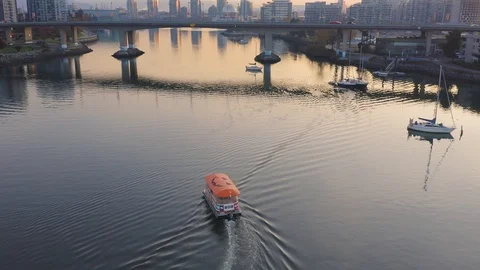 Aerial: Ferry boat docking at  False creek marina at sunrise. Vancouver, British Stock Footage 119939625