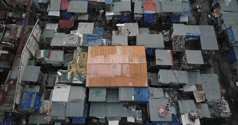 Aerial flight backtracking over slums tilting up to reveal the sea, Manila Stock-Footage 129559450
